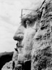 Profile of stone face on mountainside, with 3 workers.