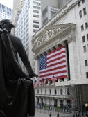 Statue facing a city building with Greek columns and huge U.S. flag